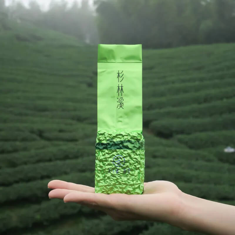 杉林溪茶葉禮袋展示,手持於茶園背景前,象徵台灣高山烏龍茶產地特色