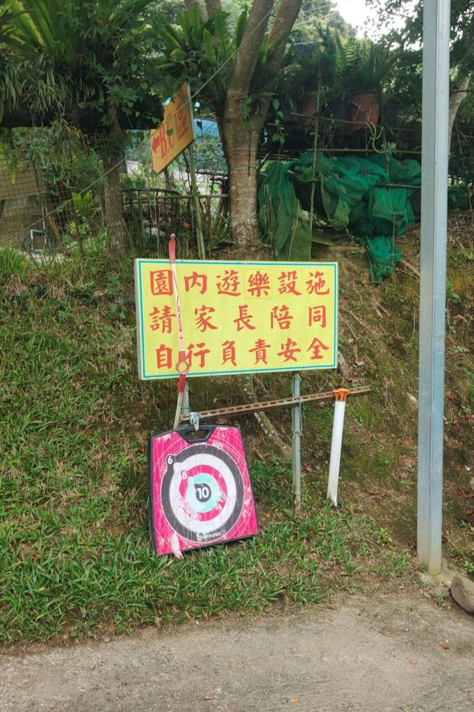 苗栗夢之谷露營區的射箭場設施，提供標靶讓親子露營的家庭體驗射箭樂趣，一旁的告示牌提醒家長需陪同注意安全。